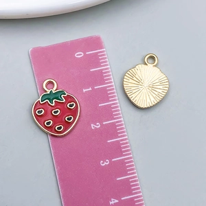Detail of red strawberry alloy pendant showing dimensions with a ruler and back texture