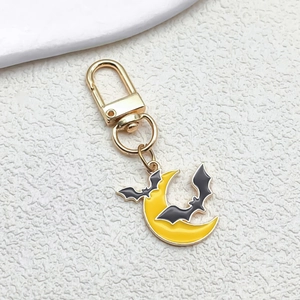 Detail of Halloween enamel keychain with yellow crescent moon and two black bats on gold alloy