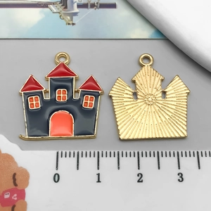 Front and back detail of a castle charm with colorful enamel and golden sunburst texture