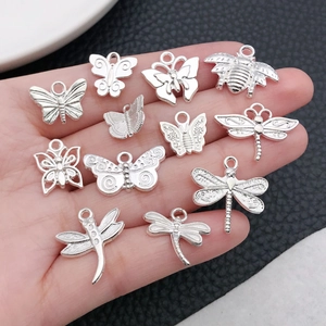Close-up of DIY silver alloy insect pendants including butterfly and dragonfly for jewelry