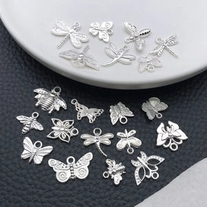Macro shot of silver alloy insect pendants including butterflies and bees on a textured surface