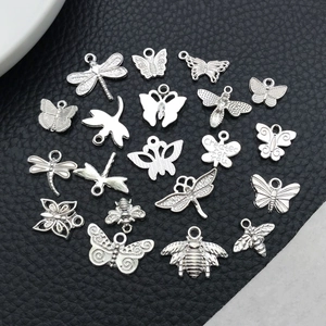 Macro shot of assorted silver insect charms including butterflies and dragonflies on leather