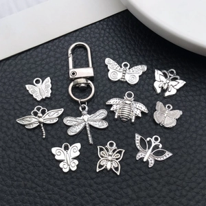 Detailed macro view of vintage silver insect charms and dragonfly keychain on black leather