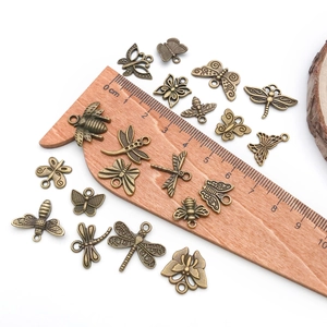 Vue détaillée de pendentifs insectes en alliage de bronze avec échelle de mesure en bois