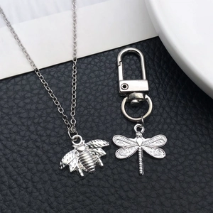 Macro detail of silver insect pendants featuring bee and dragonfly with embossed texture