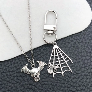 Detailopname van een zilveren ketting met schedel en een sleutelhanger met spinnenweb