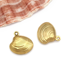 Macro shot of gold stainless steel shell charms with fine texture on a white background