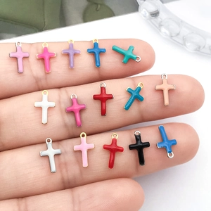Colorful enamel cross pendants for DIY jewelry making displayed on a hand for scale