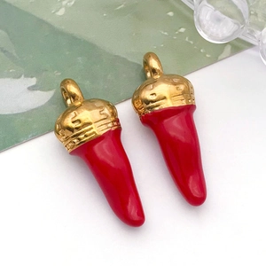 Gros plan détaillé de deux pendentifs cornicello italiens rouges avec calottes dorées