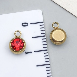 Macro view of a 6mm red zircon charm pendant on a scale for precise size reference