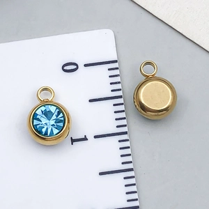Detail view of 8mm blue crystal birthstone pendant with golden stainless steel frame