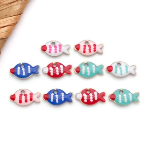 Vista macro di ciondoli marini in smalto colorato a forma di pesce con bordi dorati