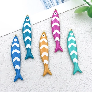 Macro view of five colorful enamel fish pendants with golden loops for DIY jewelry
