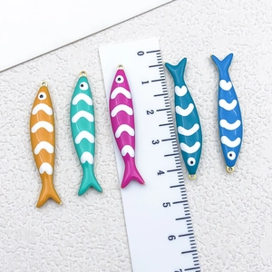 Enamel fish pendants in five colors on white background with 3.8cm measurement scale