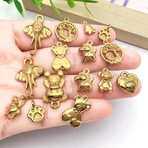Golden stainless steel animal pendants including elephant and bear charms held in hand