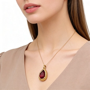Elegante vergulde ketting met een peervormige robijnrode steen en gehamerde metalen randafwerking