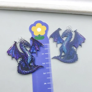 Macro detail of acrylic dragon pendants with dimensions shown on a centimeter ruler