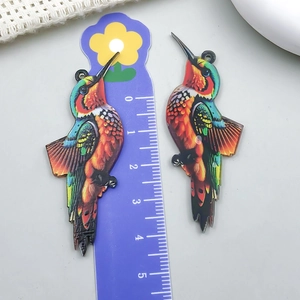 Macro detail of acrylic bird pendant with colorful feathers and size reference scale