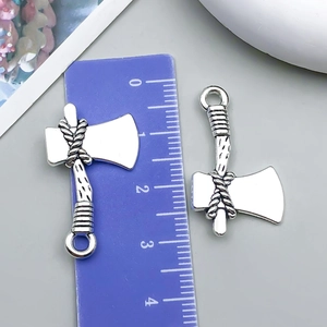 Detail view of vintage silver axe charms for DIY jewelry with ruler for scale