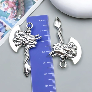 Detailed view of antique silver dragon head axe pendants with measurements on ruler