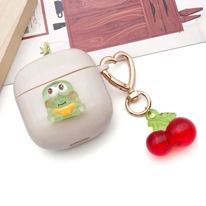 Funda de silicona crema para auriculares con rana verde y llavero de corazón dorado