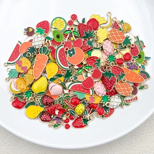Gros plan de pendentifs de fruits colorés en émail dans un plat en céramique blanc