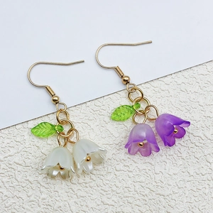 Detail view of handmade lily of the valley earrings with white and purple acrylic flowers