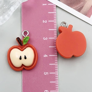 Detail of red apple resin pendants with silver loops showing front and back texture
