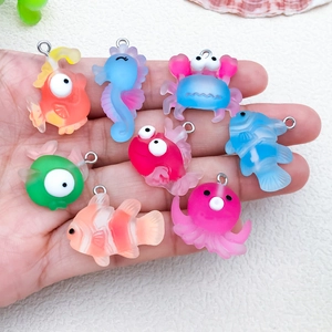 Handheld view of eight colorful resin marine animal charms with silver metal rings
