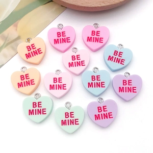 Detail of colorful resin heart charms with BE MINE engraving and metal rings