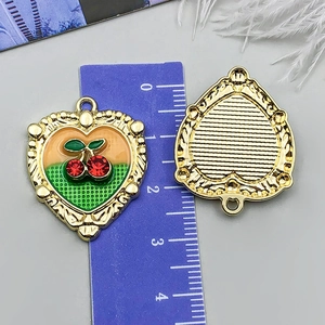 Détail du pendentif cœur aux cerises avec relief doré et strass rouges étincelants