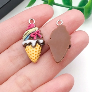 Detailed view of DIY resin ice cream cone pendants with pink bows and metal loops