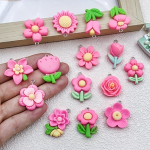 Hand holding assorted resin flower pendants including rose and sunflower for DIY crafts