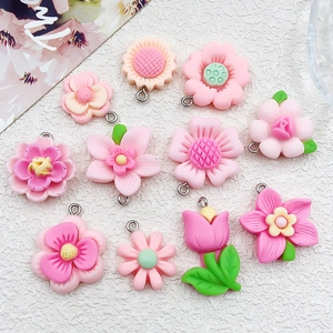 Detailed macro view of assortment of pink resin flower charms with metal loops for DIY jewelry