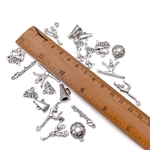 Antique silver sports cheerleader and football alloy charms set shown with scale ruler