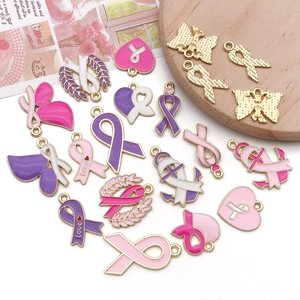 Close-up of pink enamel ribbon charms and heart pendants for DIY jewelry making
