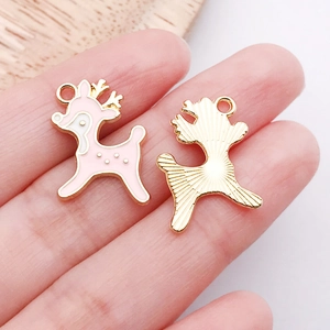Macro detail of pink enamel deer charms showing polished gold finish and textured back