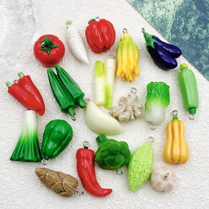 Detalle de dijes de resina con forma de vegetales y aros metálicos para joyería artesanal