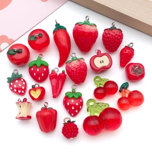 Flat lay of red resin fruit charms like strawberry and apple for DIY jewelry making