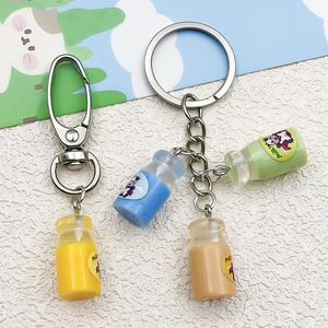 Close-up of DIY resin milk bottle keychains with cartoon cow labels and lobster clasps