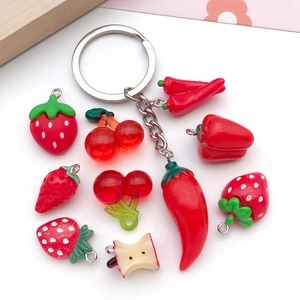 Flat lay of realistic resin fruit pendants including strawberry cherry and chili with keychain