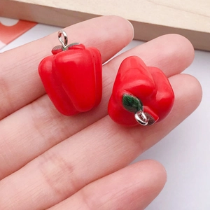 Macro view of handmade red bell pepper resin charms with silver metal rings for DIY jewelry