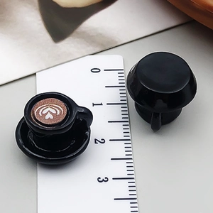 Miniatur-Kaffeetassen-Anhänger aus Harz mit Latte-Art neben einem Lineal zur Größenskala