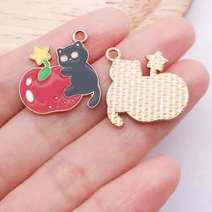 Détail d'un pendentif chat noir et fraise en alliage avec un dos texturé doré pour DIY