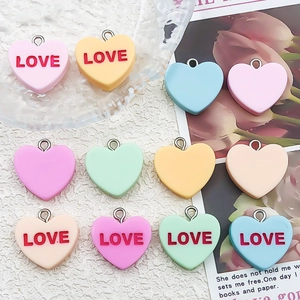 Macro shot of macaron color resin heart charms with LOVE lettering and metal rings