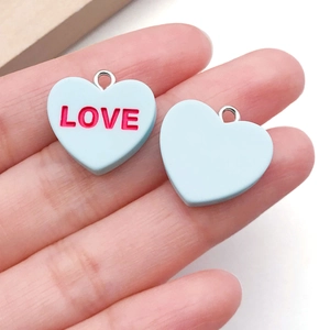 Macro shot of light blue heart pendants with red LOVE text and silver metal rings