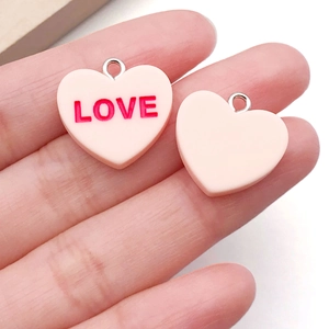 Close-up of pink resin heart charms with LOVE lettering for DIY jewelry making