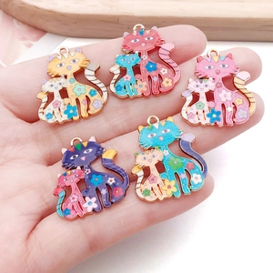 Pendentifs chat colorés en alliage avec motifs floraux émaillés présentés sur la main