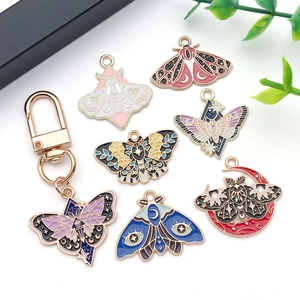Detailed view of colorful enamel moth and butterfly pendants with celestial motifs