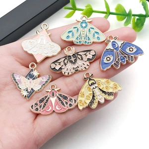 Colorful enamel butterfly pendants with celestial patterns held in hand for DIY jewelry